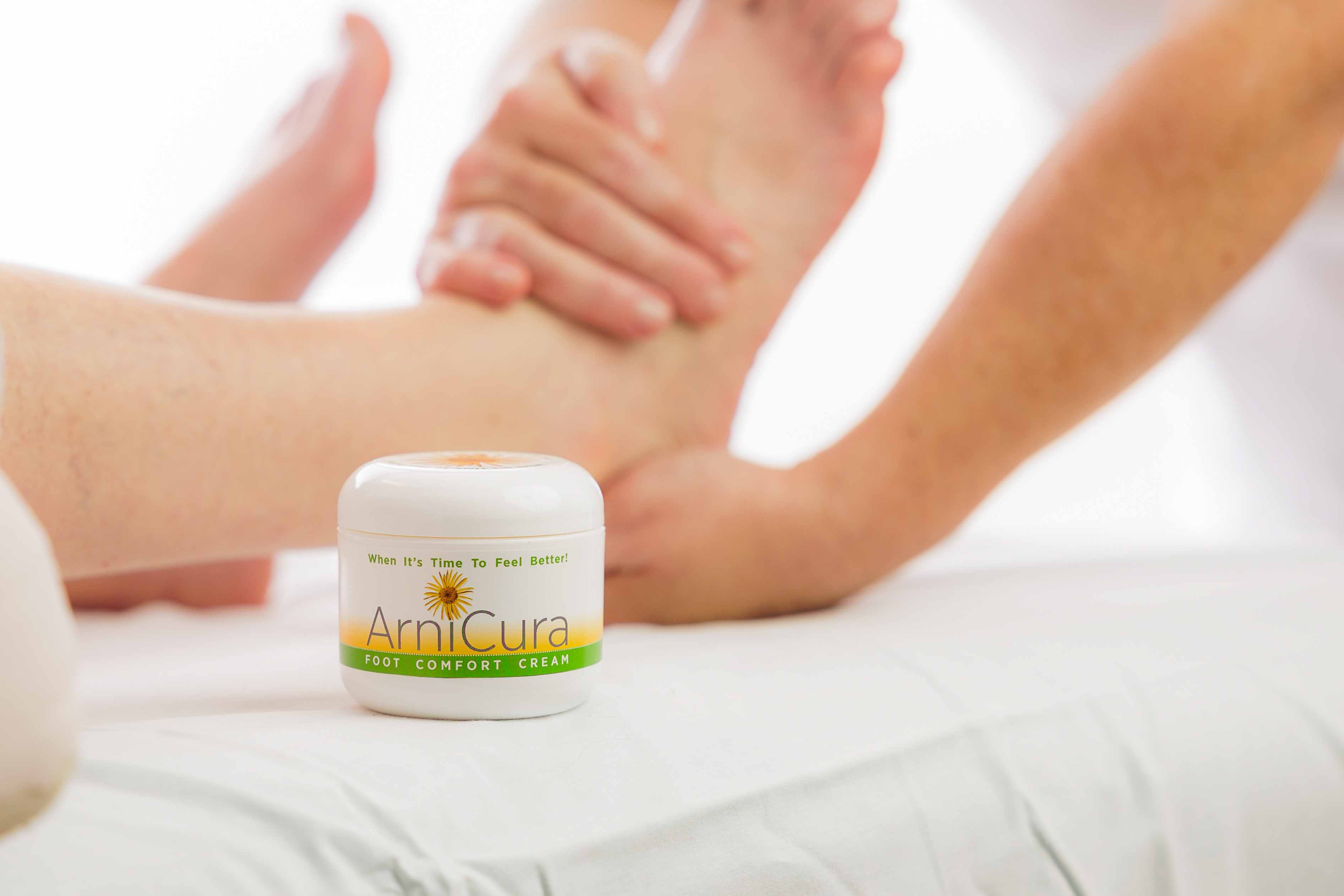 ArniCura Foot Comfort Cream β natural Arnica-based foot comfort cream jar with professional foot massage in background