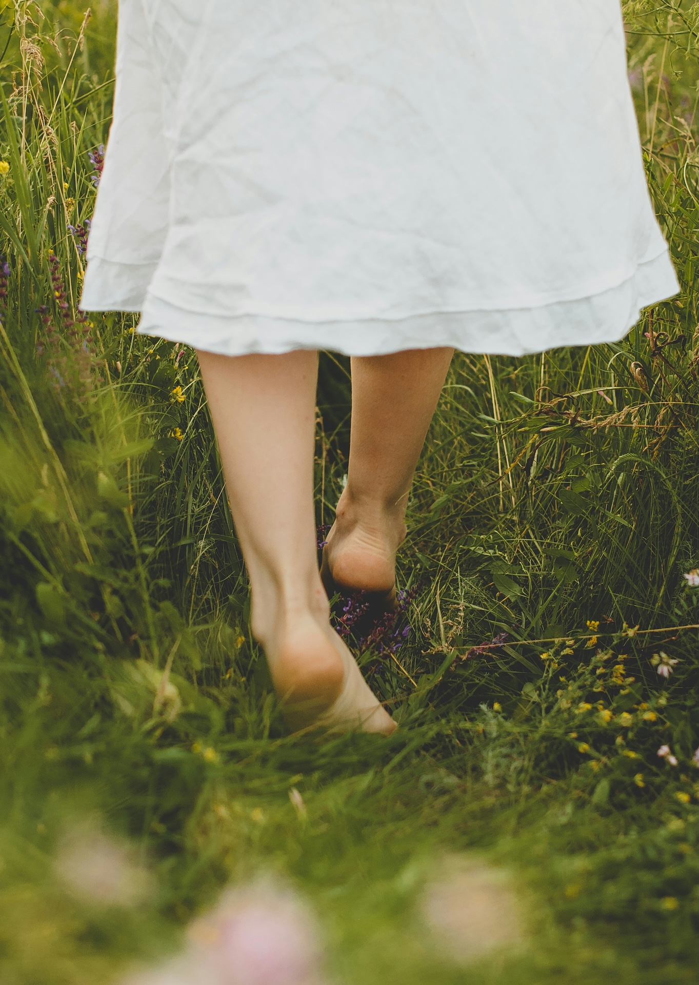 Woman walking barefoot through grass β the natural comfort and freedom that ArniCura helps restore